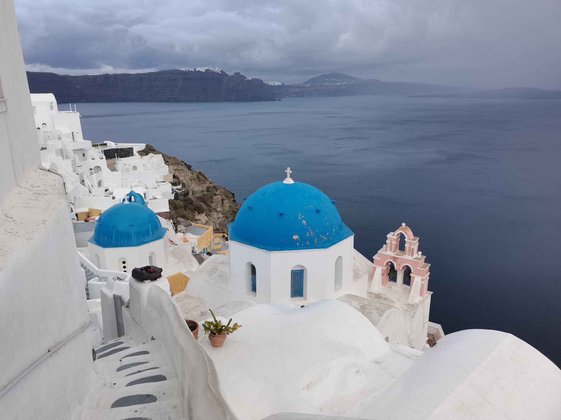 Breathtaking view of Santorini's blue domes overlooking the Aegean Sea on a cloudy day.